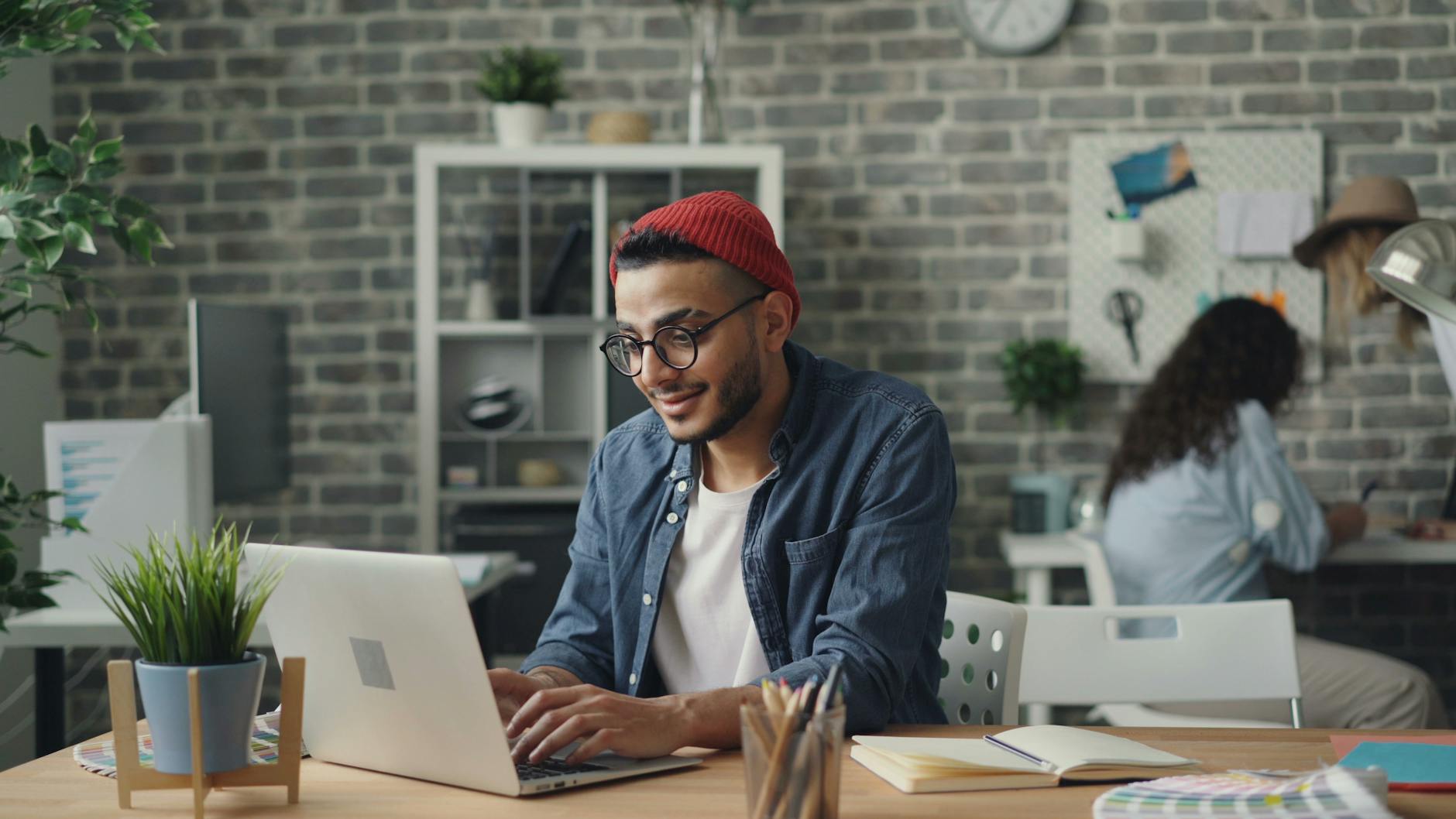 a man in a red hat is working on his laptop