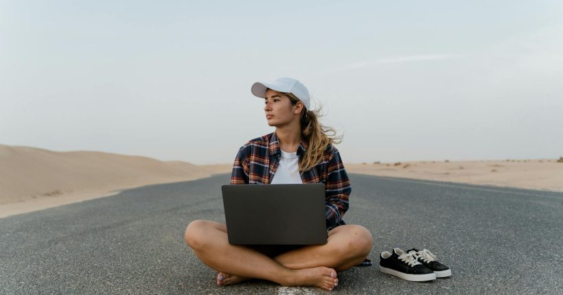 a woman sitting on the road with her laptop