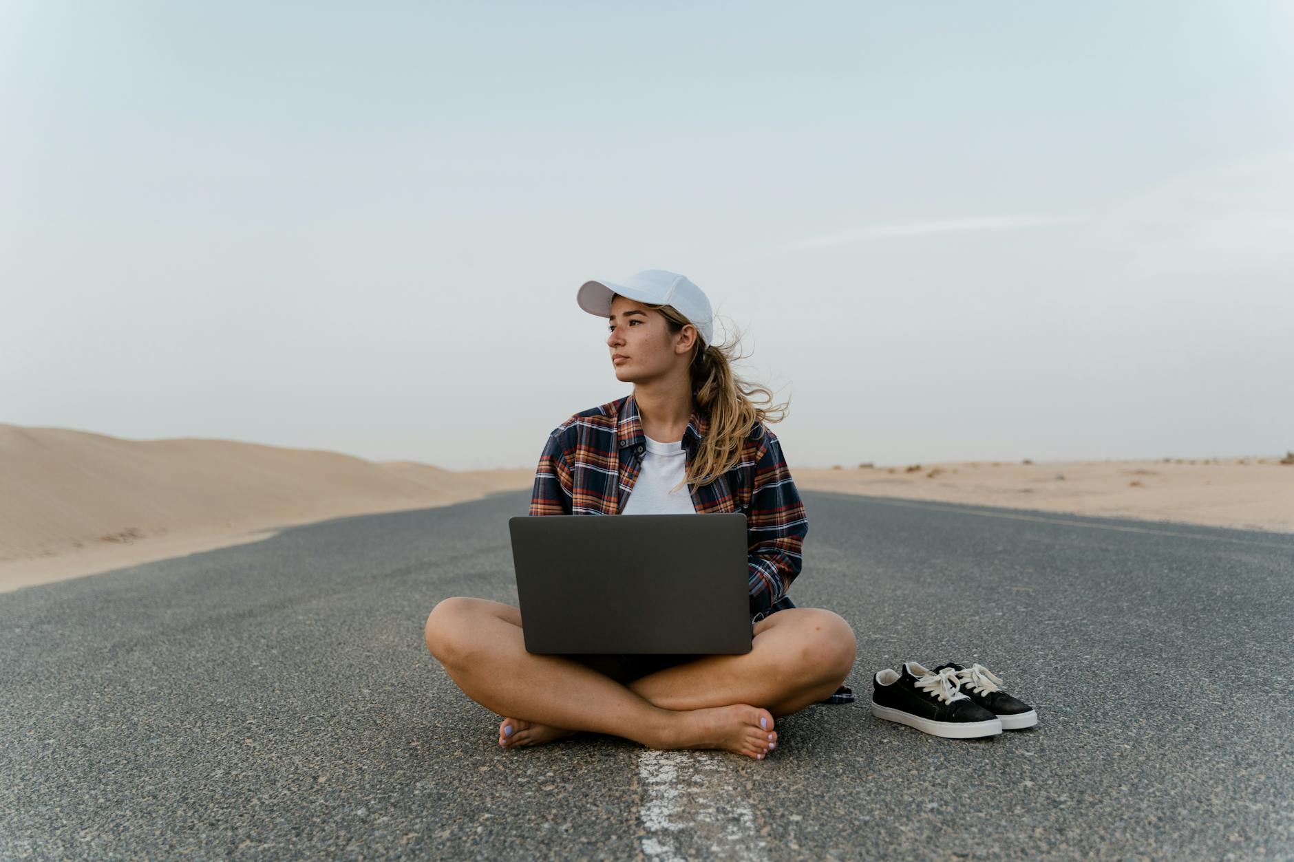 a woman sitting on the road with her laptop