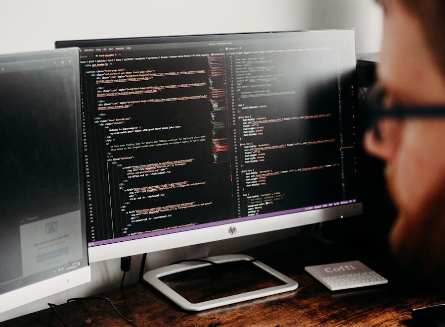 Focused software developer at desk coding with multiple monitors in a modern workspace.