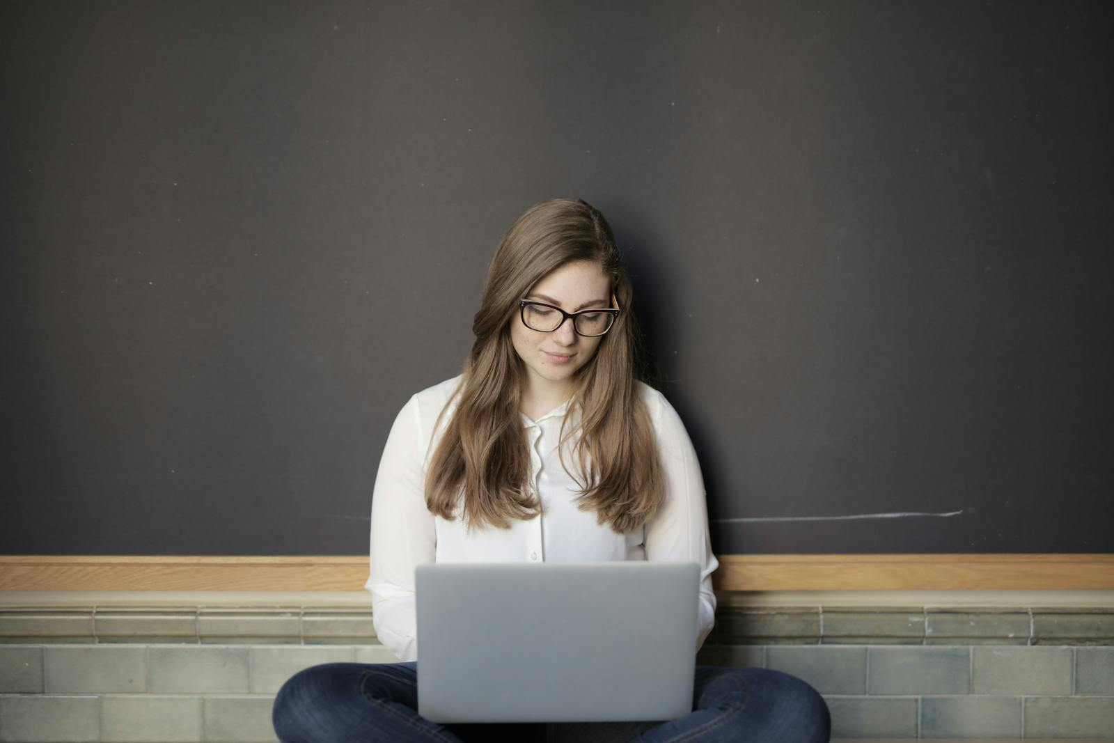 A young woman sitting indoors using a laptop, embodying the freelance and digital nomad lifestyle.