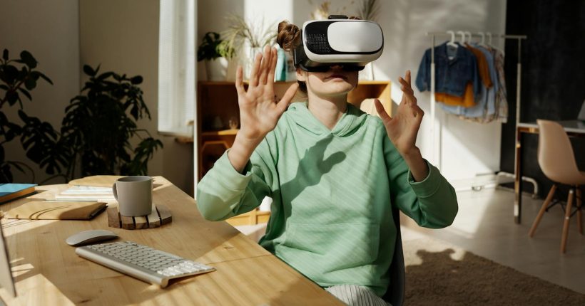 Teenage girl experiencing virtual reality at home with a VR headset, surrounded by modern tech.