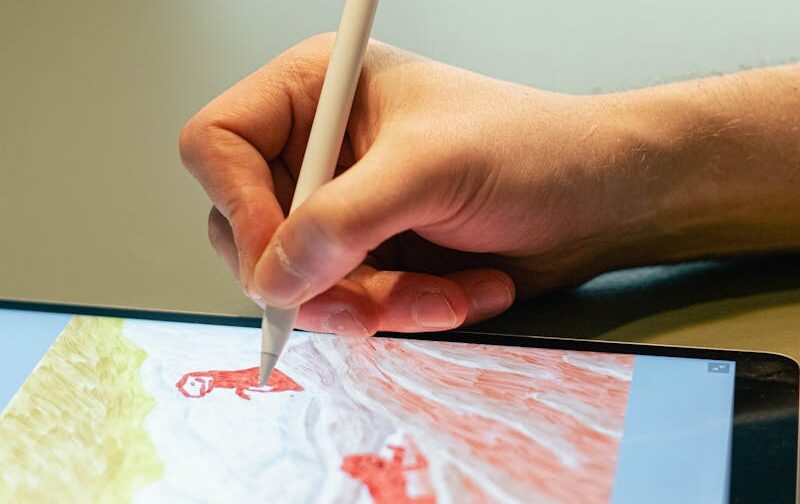 Close-up of hand drawing on tablet screen with stylus, showcasing digital artistry.
