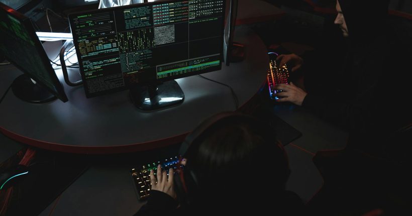 A group of people in a dark room working on computers, related to cybersecurity.