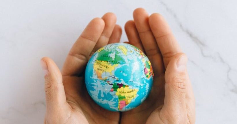 Close-up of hands gently holding a small globe representing global unity and care.