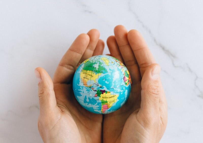 Close-up of hands gently holding a small globe representing global unity and care.