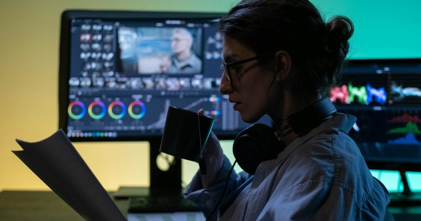 A concentrated editor sipping tea while reviewing papers in a modern editing studio.