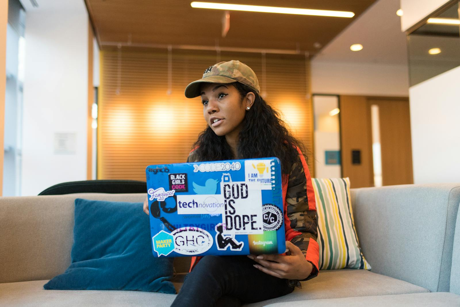 A young woman engaged with her laptop, showcasing tech culture in a stylish office.