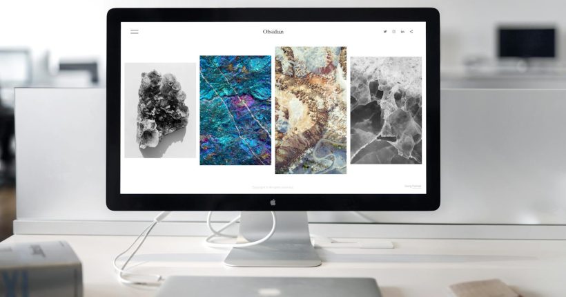 A contemporary office desk setup featuring a sleek computer monitor displaying abstract artwork.