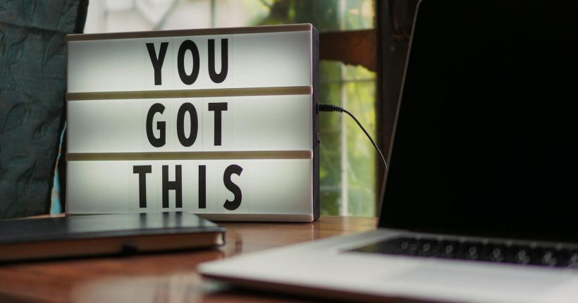 Lit sign with 'You Got This' alongside laptop on office desk.