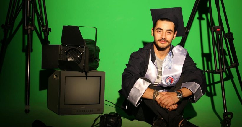 Graduate in studio setting with camera equipment, symbolizing creative future paths.