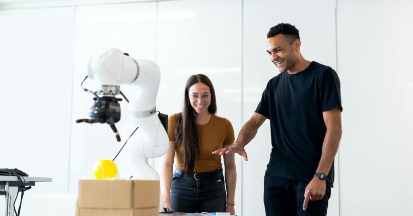 Two engineers collaborating on testing a futuristic robotic prototype in a modern indoor lab.