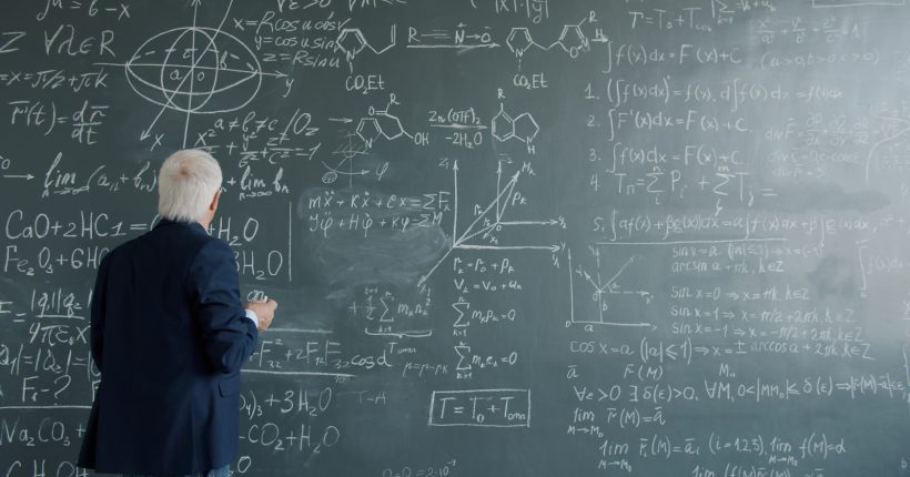 Professor writing complex formulas on a chalkboard