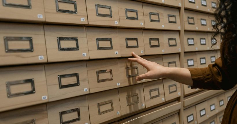 A person organizing wooden drawers in an archive room with a focus on storage.