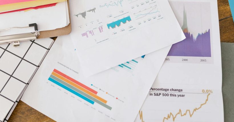 Close-up of business analytics charts and graphs on papers and clipboard.
