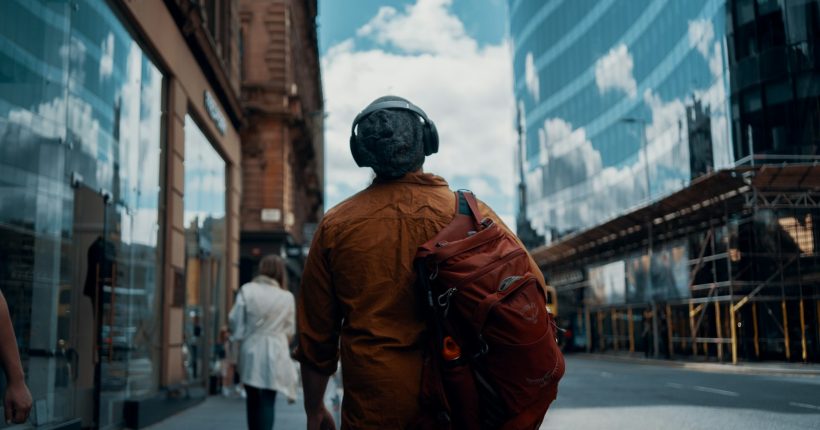 man in orange jacket walking on street during daytime