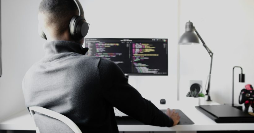 man in black long sleeve shirt wearing black headphones sitting on chair