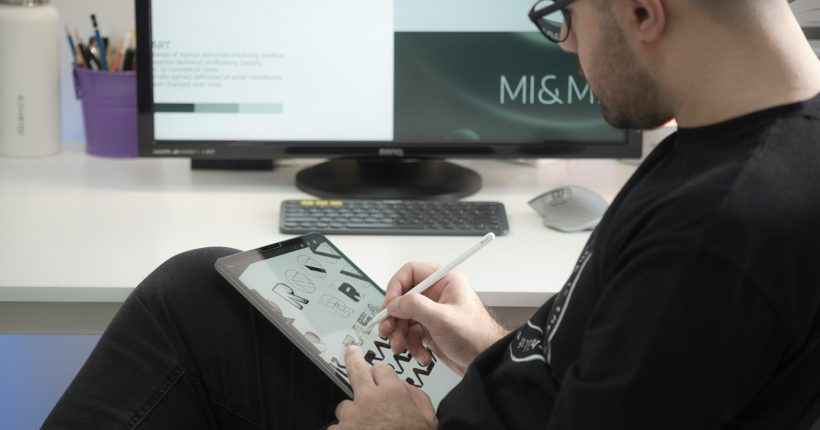 man in black long sleeve shirt sitting beside black flat screen computer monitor
