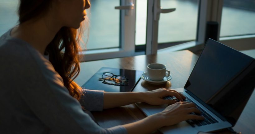 woman sitting beside table using laptop
