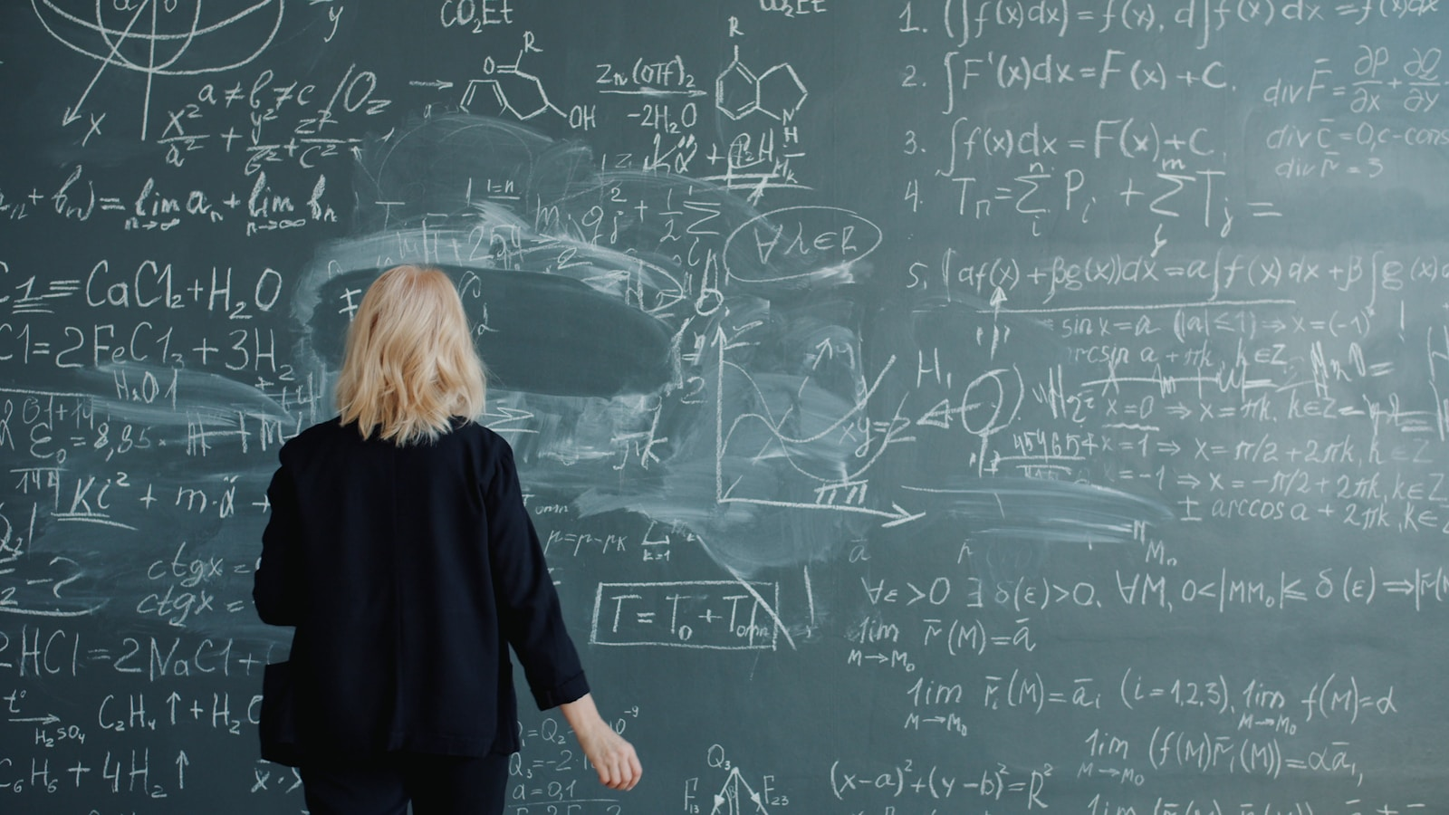 Woman looking at a blackboard with complex math equations.