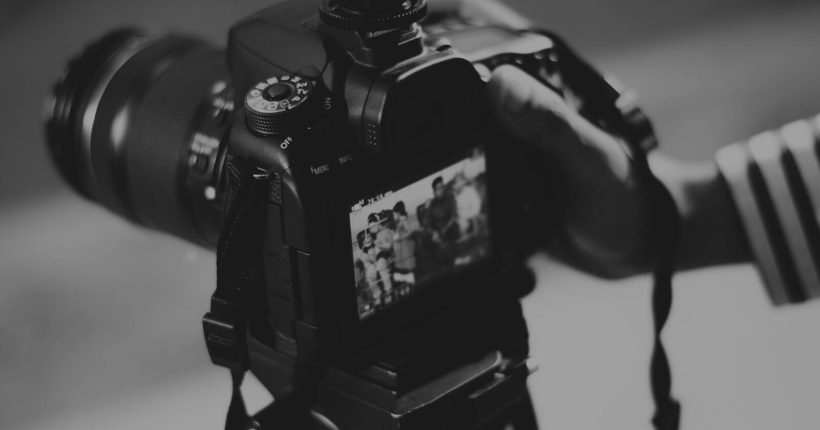 Black and white image of a DSLR camera capturing people in focus, showcasing photography professionalism.