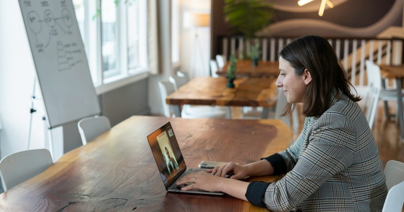 woman in gray and white striped long sleeve shirt using silver macbook
