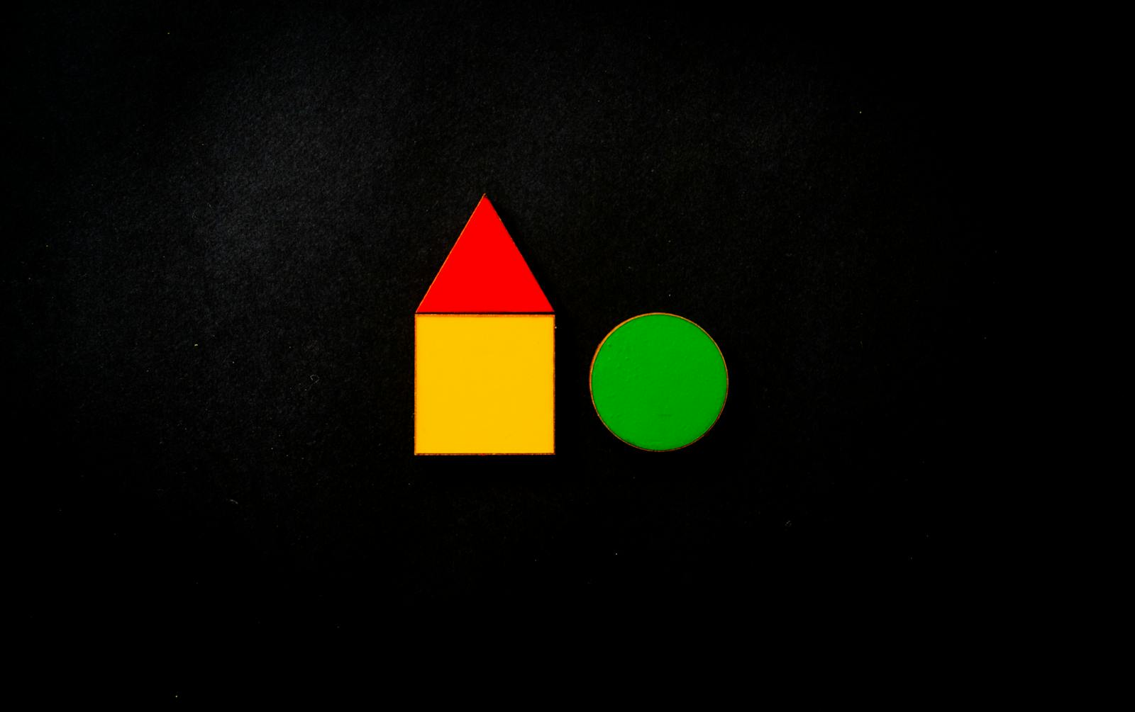 Colorful geometric shapes including a red triangle and yellow square on a black background.