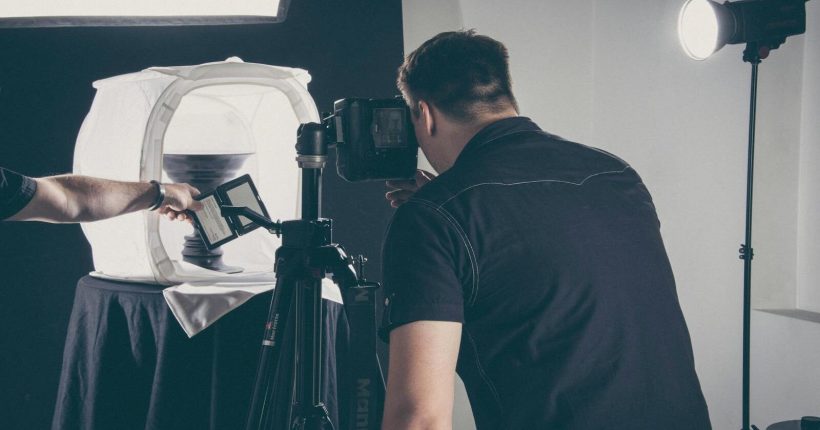Photographer capturing product in a studio setup with lighting gear and camera.
