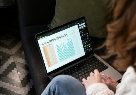 A woman reviewing 2024 social media goals on a laptop at home.