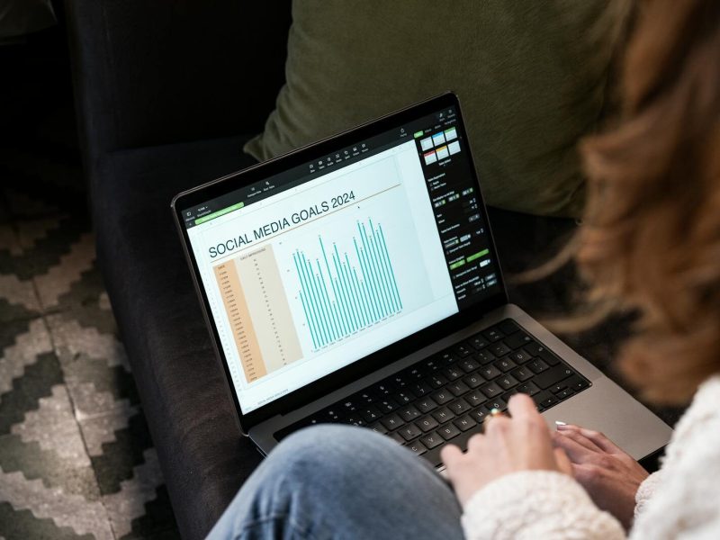 A woman reviewing 2024 social media goals on a laptop at home.