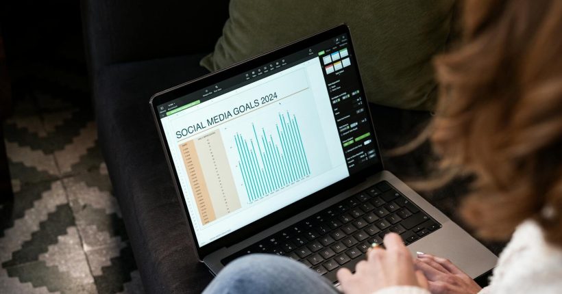 A woman reviewing 2024 social media goals on a laptop at home.