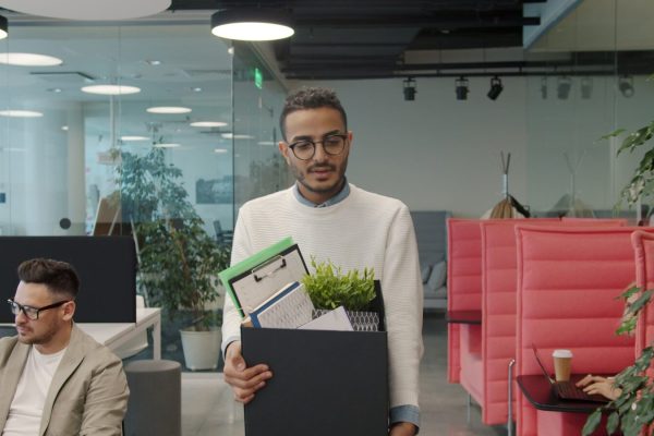 Man carrying box of belongings in modern office
