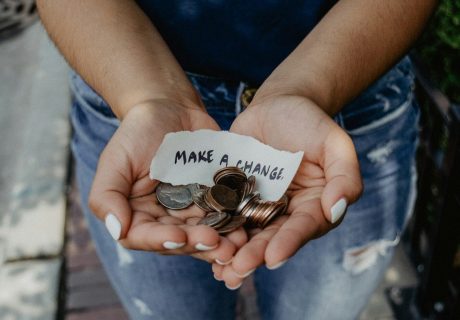 person showing both hands with make a change note and coins