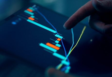 Fingers interacting with a stock market graph on a tablet.