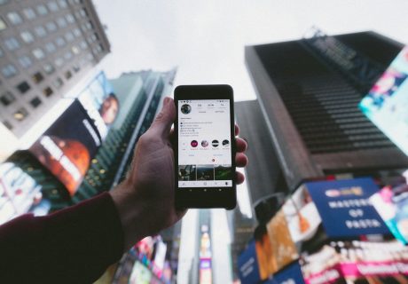 high angle photo of person holding turned on smartphone with tall buildings background