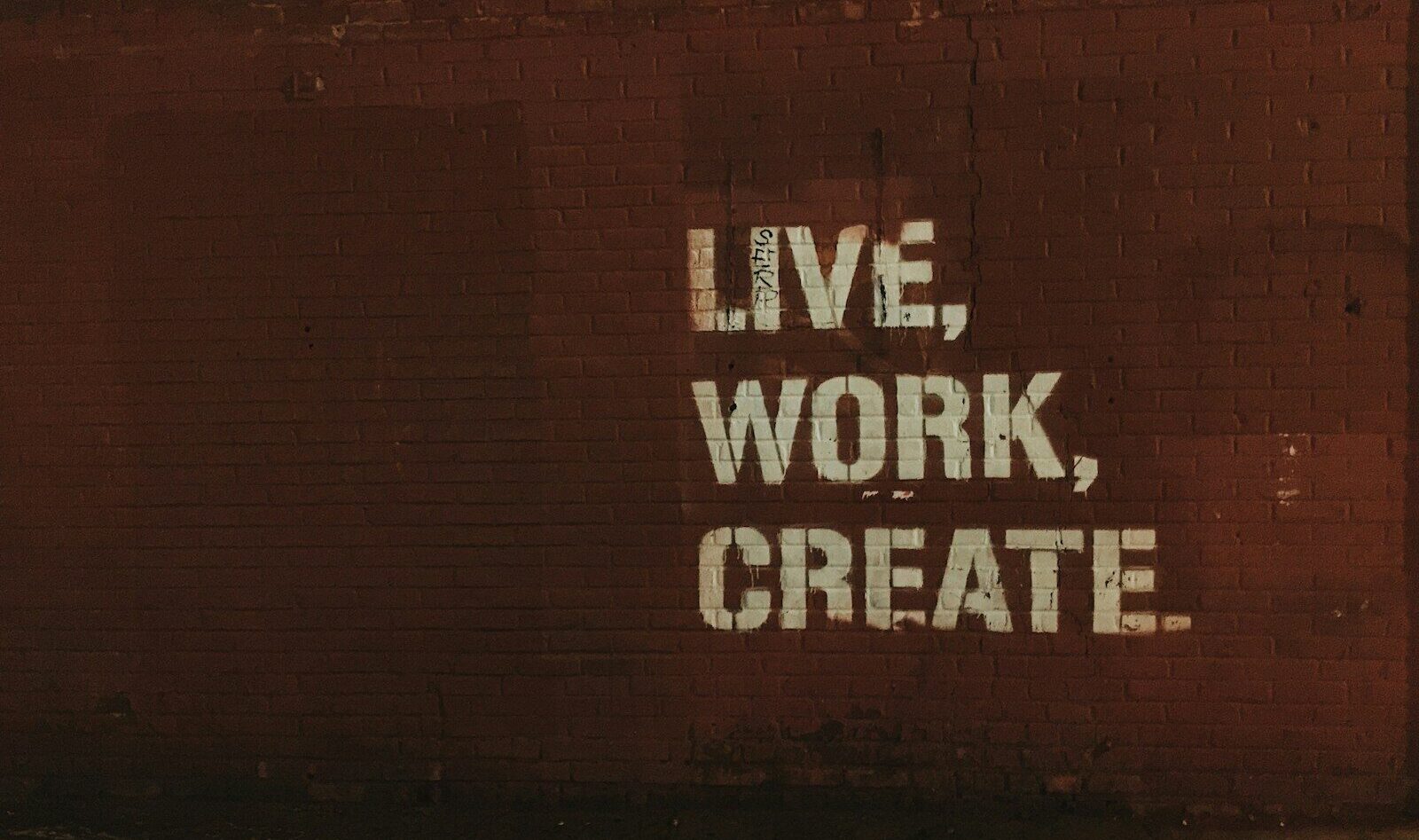 red brick wall with live, work, create. quote