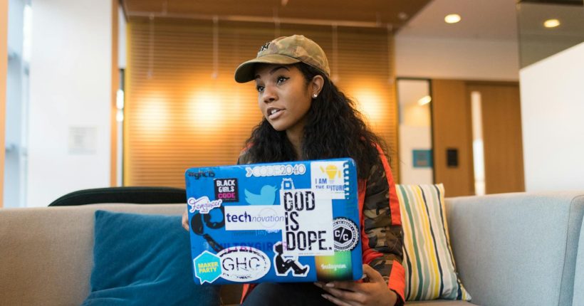 A young woman engaged with her laptop, showcasing tech culture in a stylish office.