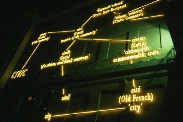 Neon-lit structure at night displaying historical language connections. Modern and abstract lighting art.