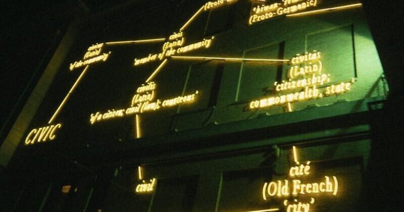 Neon-lit structure at night displaying historical language connections. Modern and abstract lighting art.