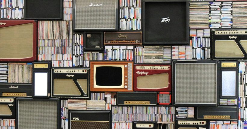 A wall of vintage speakers and TVs surrounded by books and records in a creative display.