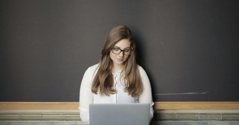 A young woman sitting indoors using a laptop, embodying the freelance and digital nomad lifestyle.