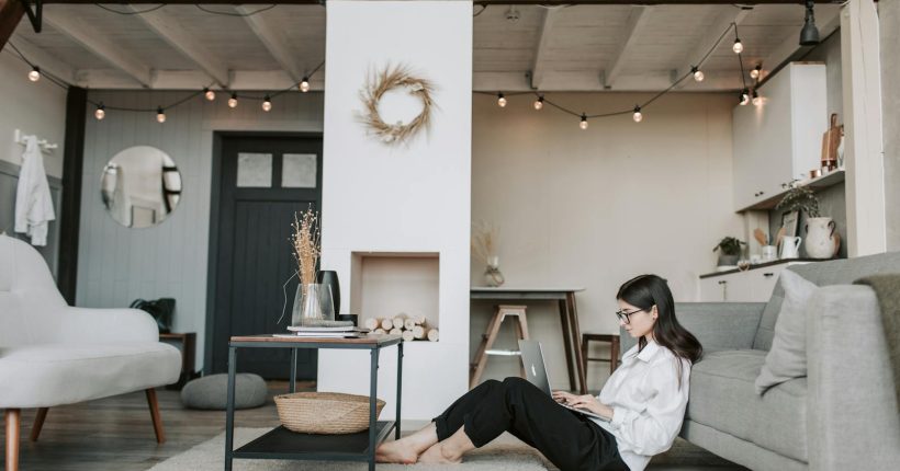 Cozy loft apartment with a woman working on a laptop, showcasing modern remote work lifestyle.
