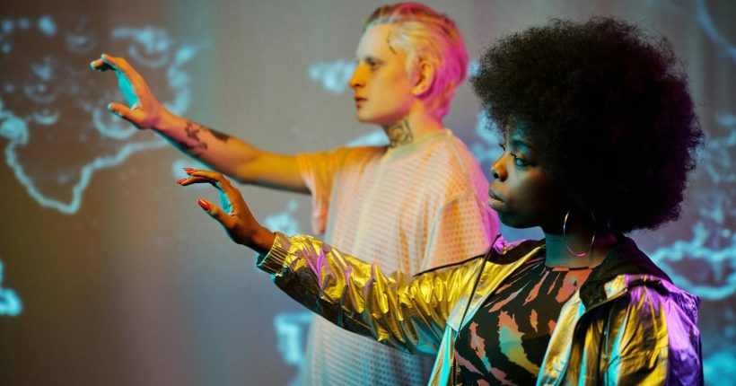 Two adults interacting with virtual screens in futuristic setting.
