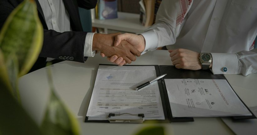 two people shaking hands over a piece of paper