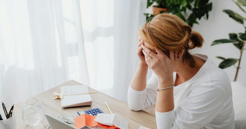 Woman stressed over financial receipts at a desk, dealing with expenses and calculations.