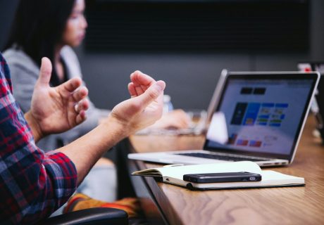 person gesturing during meeting with laptop