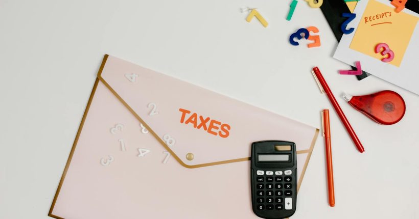 Flat lay of a tax preparation workspace with calculator, envelope, and colorful numbers.