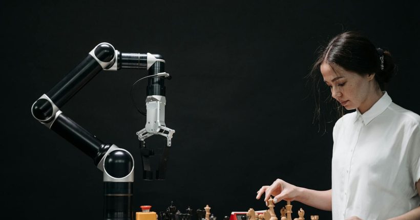 A woman plays chess against a robotic arm, showcasing AI innovation in a modern setting.