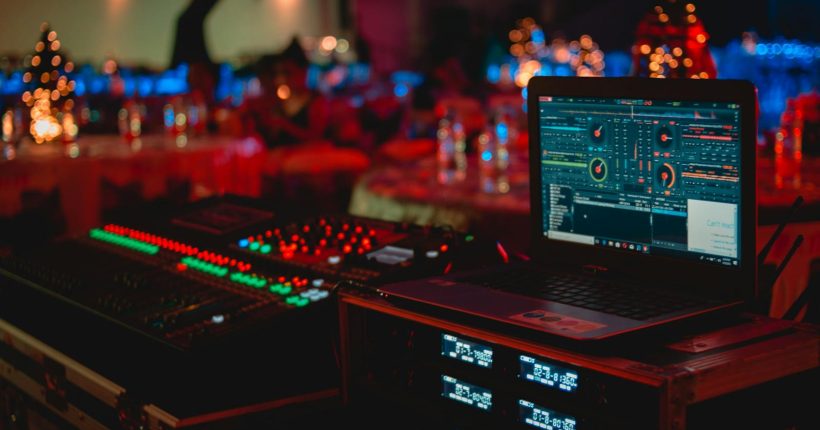 Vivid DJ setup with laptop and sound mixer at a lively indoor event.