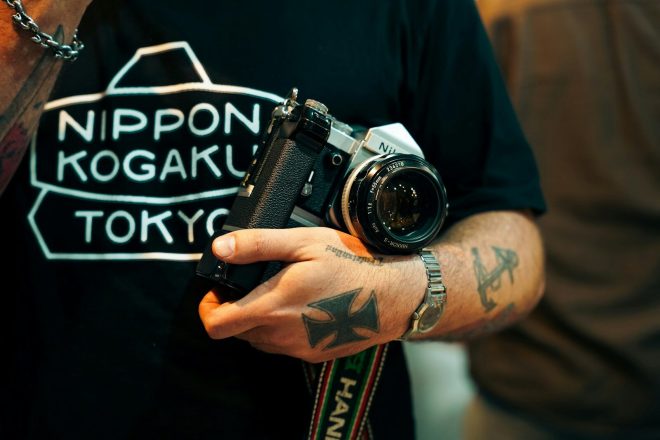 Man with tattoos holds vintage camera